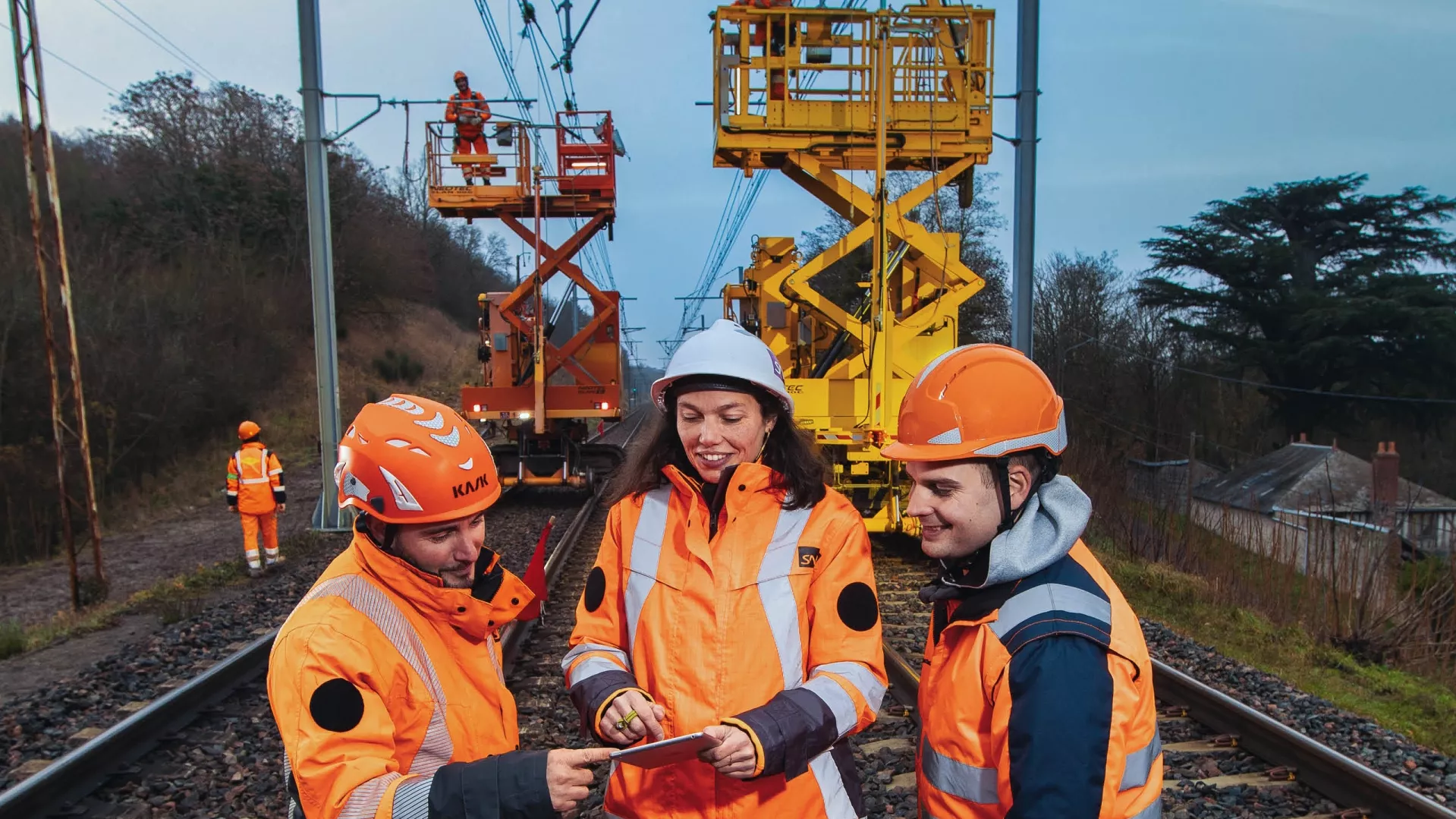 Une femme et deux hommes font un briefing sur un chantier ferroviaire